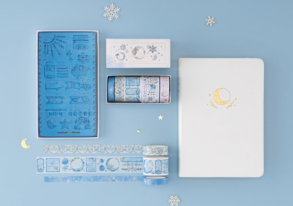 Flatlay of Winter Moonflower bullet journal notebook with blue bullet journal stencil set and winter moonflower washi tape