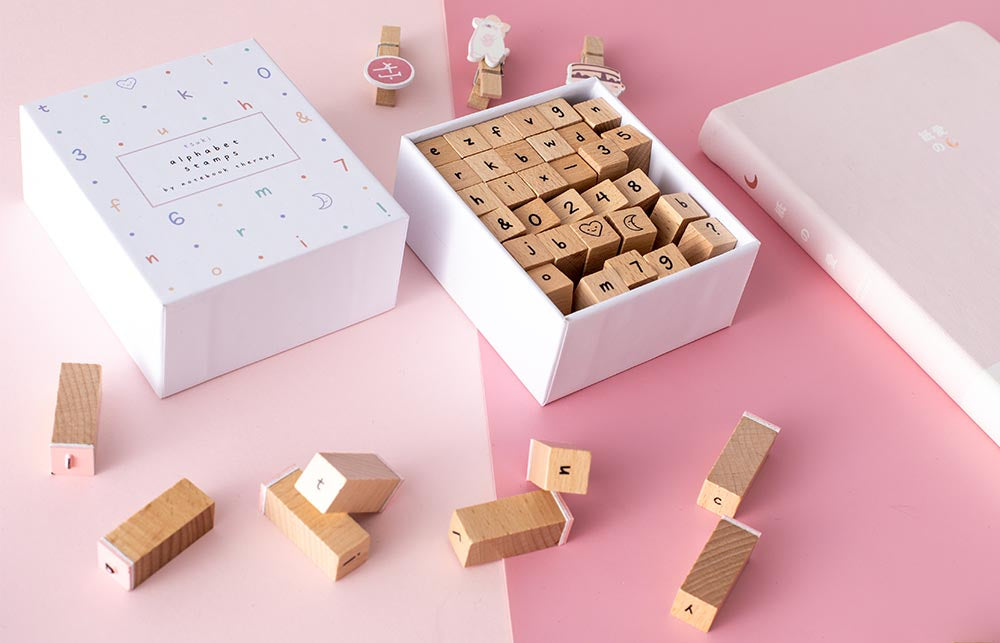 Alphabet Stamps on a pink table with a pink bullet journal