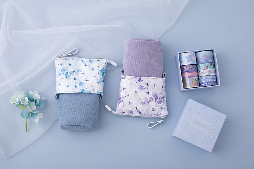 Tsuki Endless Summer Pop-Up pencil cases in petal blue and lilac bloom with Tsuki Endless Summer washi tape set with netting with blue hydrangea flowers on light blue background