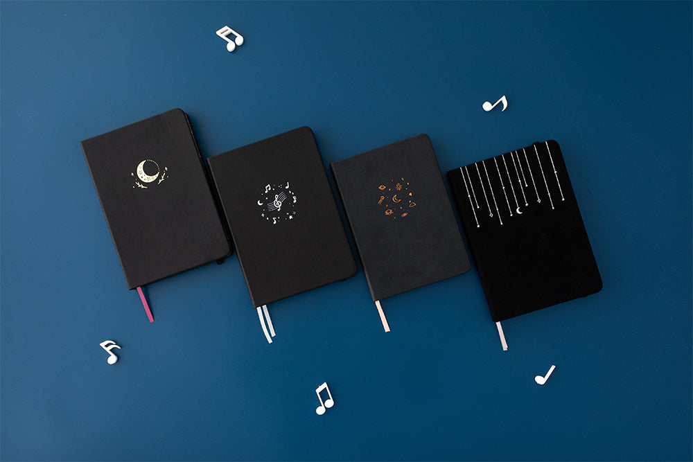 Tsuki Lunar Notes bullet journal with 3 other tsuki notebooks with music notes image on navy blue background
