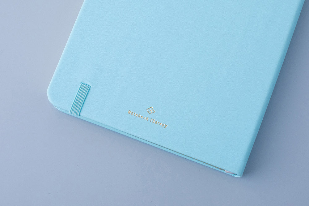 Close up of the back cover of Tsuki Endless Summer Limited Edition Bullet Journal in Petal Blue on light blue background