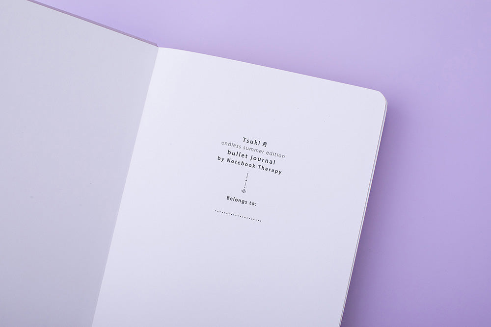 Close up of open front page of Tsuki Endless Summer Limited Edition Bullet Journal on lilac background