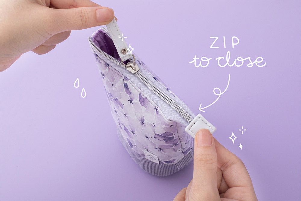 Close up of zip to close Tsuki Endless Summer Pop-Up pencil case in lilac bloom held in hands on lilac background