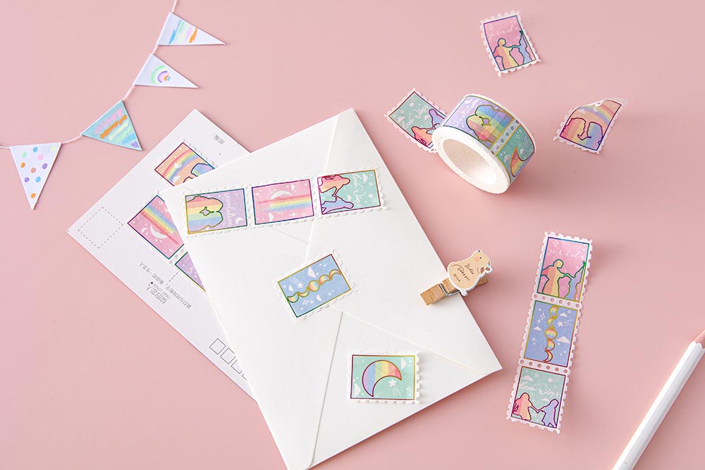 Tsuki Rainbow Pride Washi Tape on letter envelope with postcard and pencil and wooden bear peg and bunting on light pink background