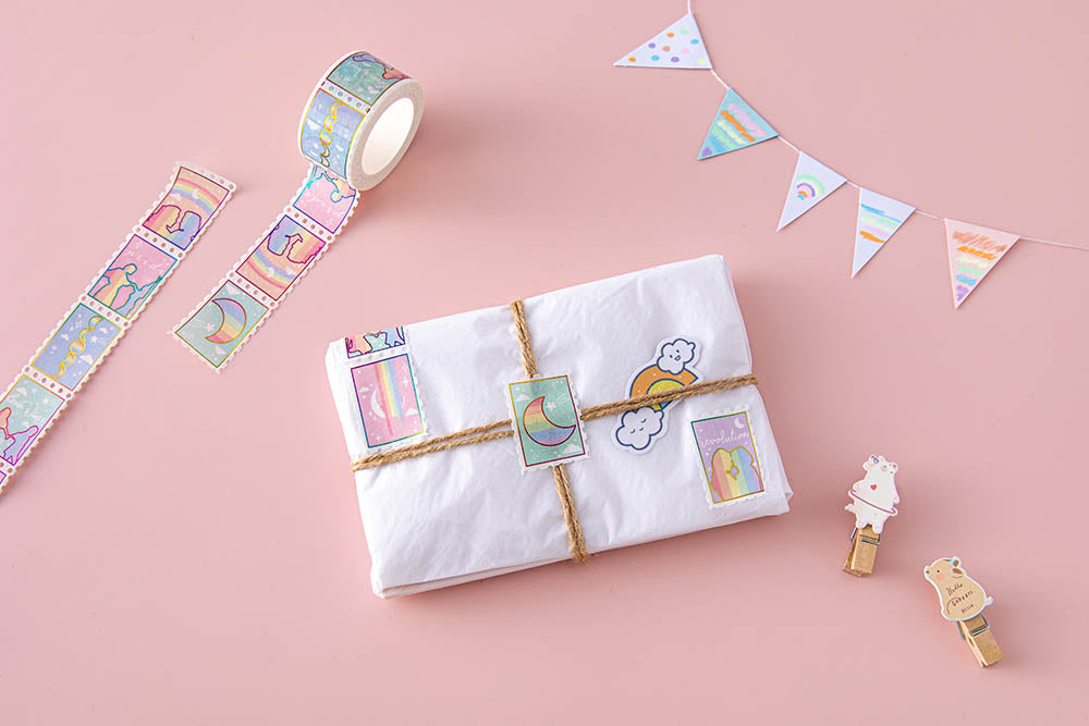 Tsuki Rainbow Pride Washi Tape on small gift wrapped parcel with twine and stickers with bunting and wooden pegs on light pink background