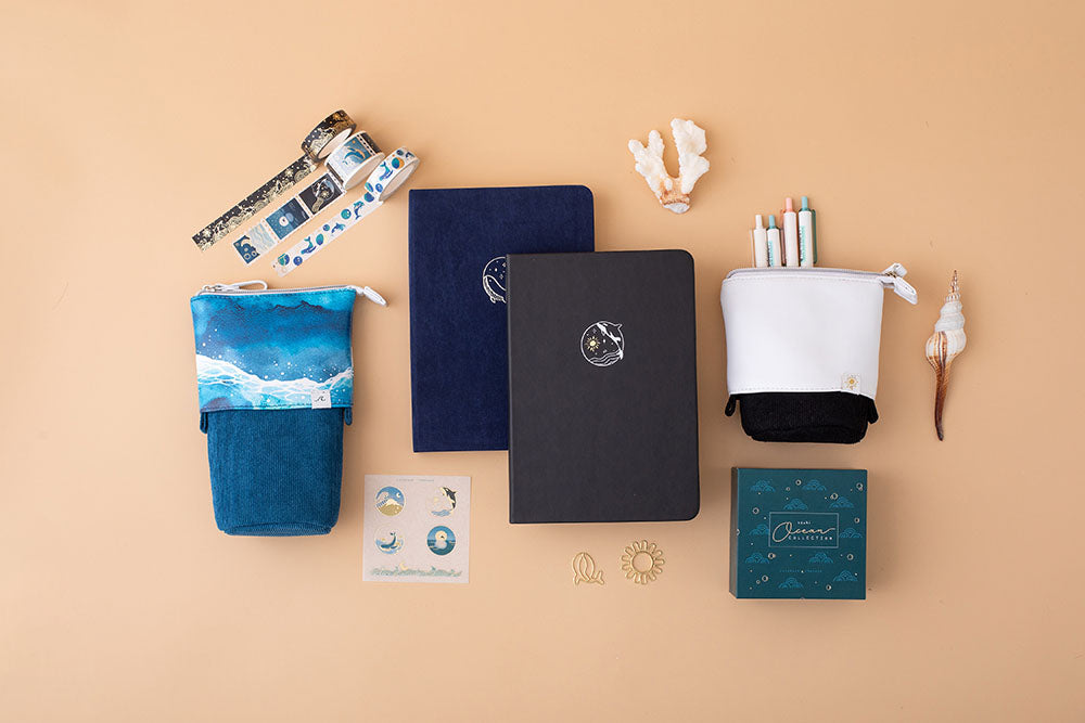 Tsuki deep black vegan leather Playful Orca limited edition notebook with seashells and free gift with Ocean pop up standing pencil case and Ocean Washi tapes and sticker set and deep blue Gentle Giant luxury edition bullet journal on peach background