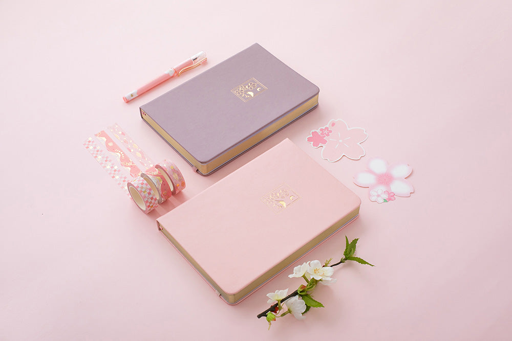 Blush pink and petal pink sakura themed bullet journal notebooks on pink backgrounds with cherry blossom decorations