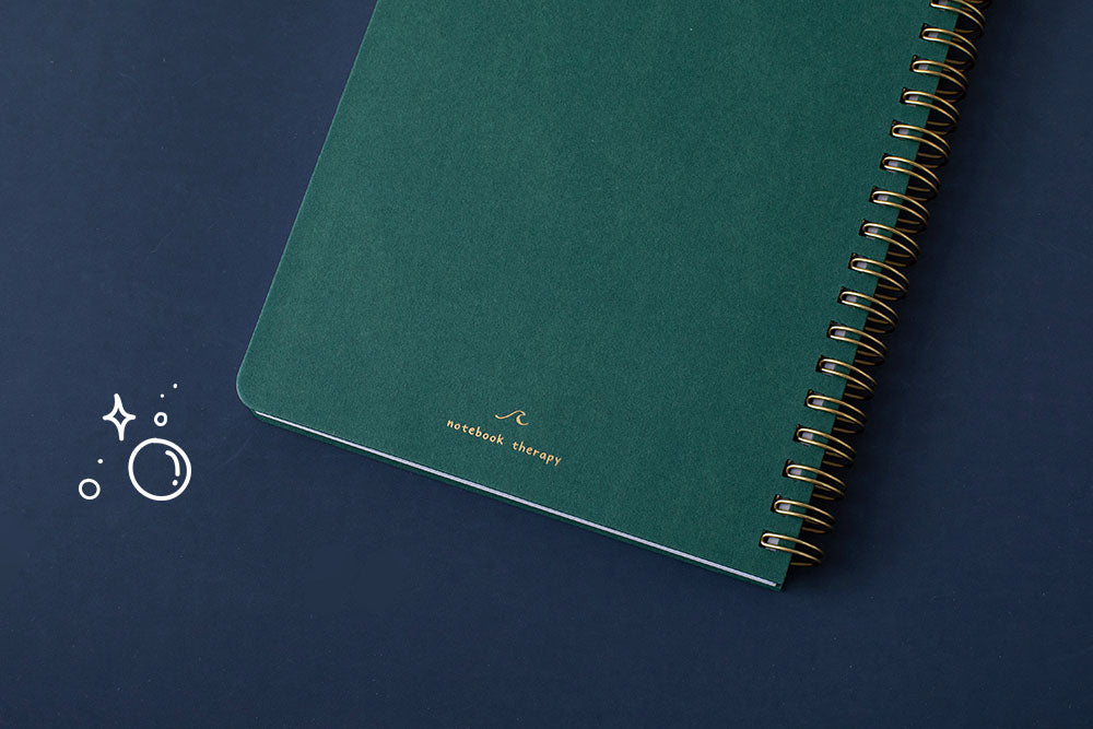 Close up of the back cover of Tsuki Ocean Edition Ring Bound notebook in deep teal on dark blue background