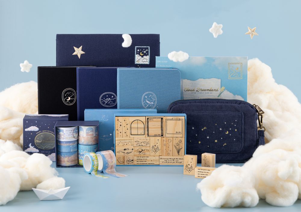 Cloud Dreamland collection flatlay on sky blue background including 3 notebooks, stamp set, washi tape set, travel pouch, notebook pouch and scrapbook set