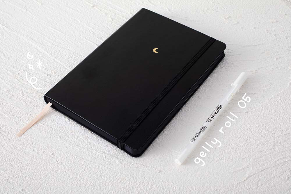 sakura white gelly roll 05 next to black page dot griid notebook