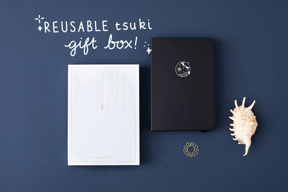 Tsuki deep black vegan leather Playful Orca limited edition notebook with eco-friendly reusable gift box and seashell and free sunshine gift on dark blue background