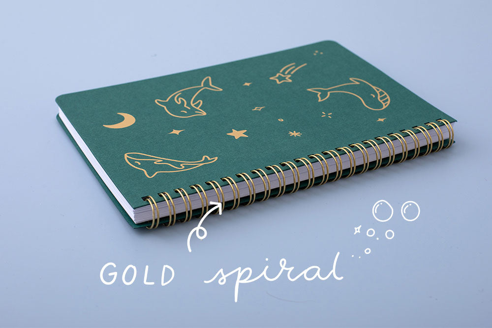 Tsuki Ocean Edition Ring Bound notebook in deep teal with gold spiral spine on blue background