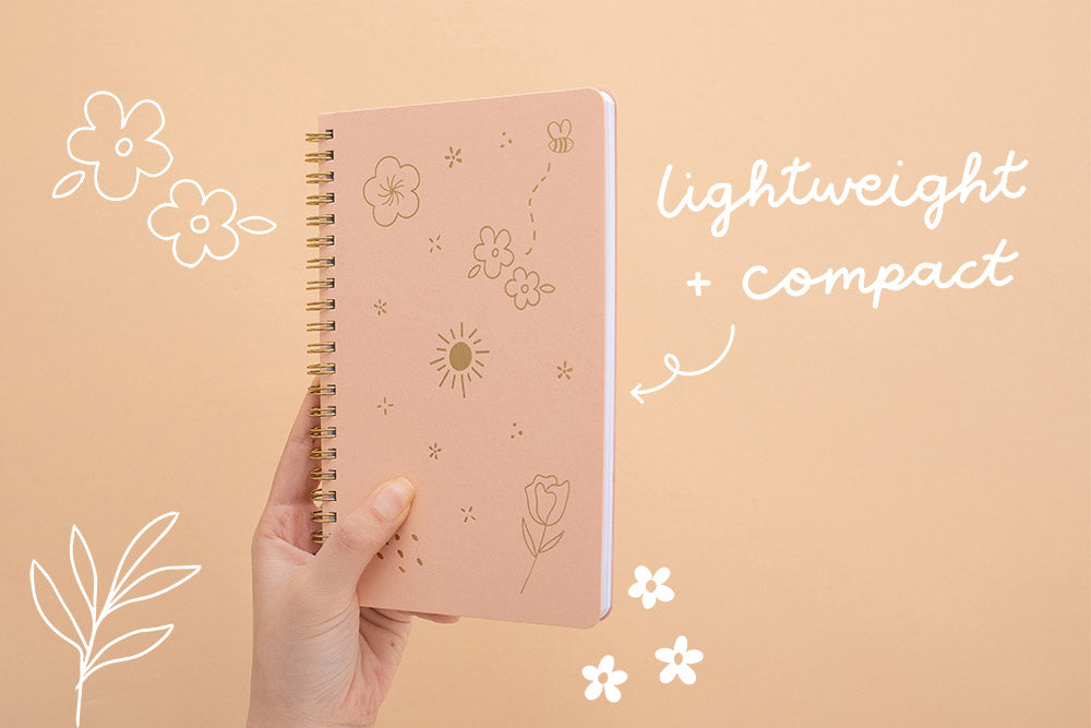 Tsuki Floral honey peach ringbound bujo held in hand on peach background