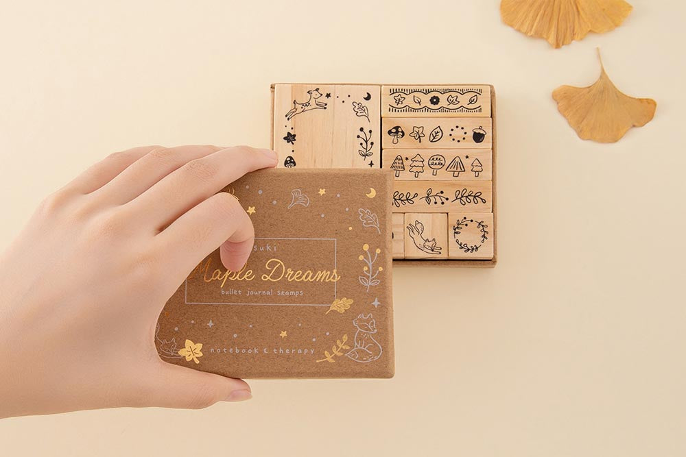 Tsuki ‘Maple Dreams’ Bullet Journal Stamp Set held in hands with autumn leaves in cream background