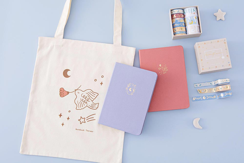 Tsuki Moonflower Collection including ‘Suzume’ Limited Edition Bullet Journal and ‘Full Bloom’ Limited Edition Notebook and ‘Moonflower’ Washi Tape Set and ‘Moonflower’ Tote Bag with star and moon on light blue background