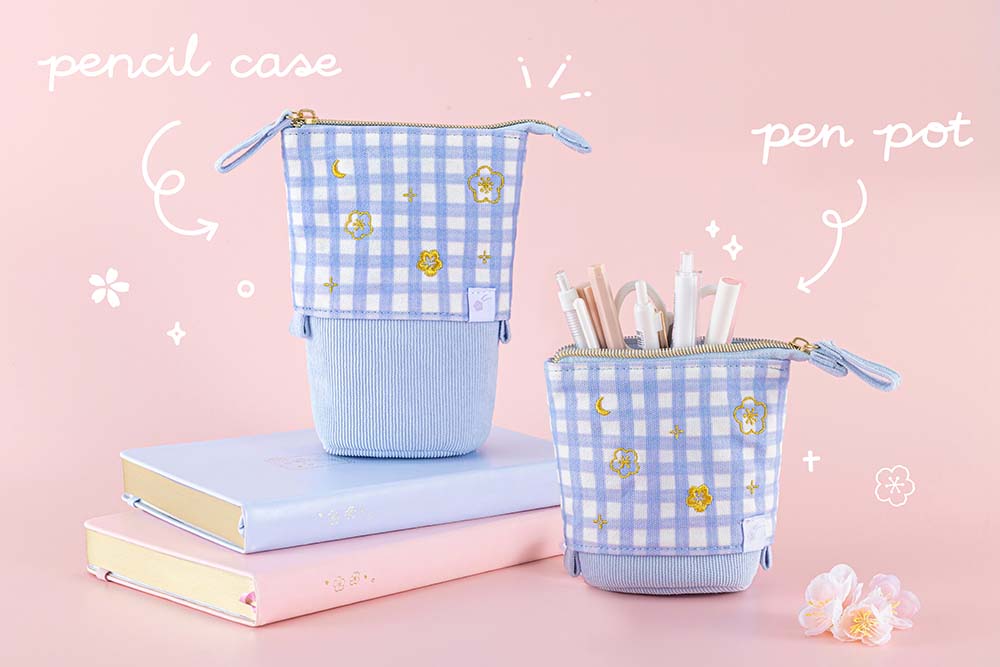 Two Tsuki ‘Sakura Journey’ Pop-Up Pencil Cases as pen pot and pencil case with pens inside with Tsuki ‘Sakura Journey’ Limited Edition Bullet Journal and Tsuki ‘Lunar Blossom’ Limited Edition Bullet Journal with cherry blossoms in light pink background