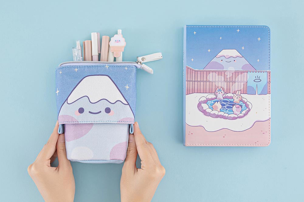 Tsuki ‘Four Seasons’ Fuji Pop-Up Pencil Case by Notebook Therapy x Milkkoyo held in hands with Tsuki ‘Four Seasons: Winter Edition’ Bullet Journal on light blue background