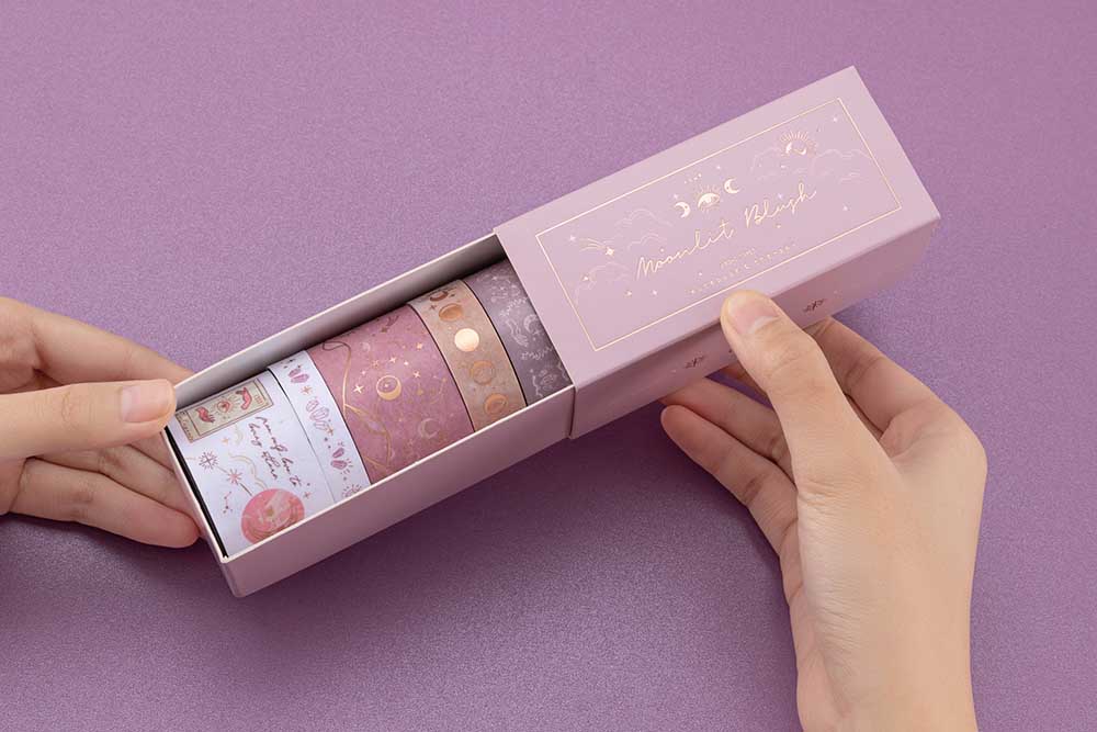 Close up of Tsuki ‘Moonlit Blush’ Washi Tape Set held in hands in purple background