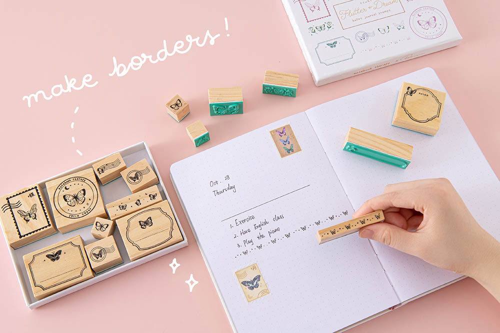 Tsuki ‘Flutter + Dream’ Bullet Journal Stamp Set by Notebook Therapy x Pelinkan to make borders held in hand on open Tsuki Cloud White ‘Flutter + Dream’ Limited Edition Bullet Journal by Notebook Therapy x Pelinkan on pastel pink background