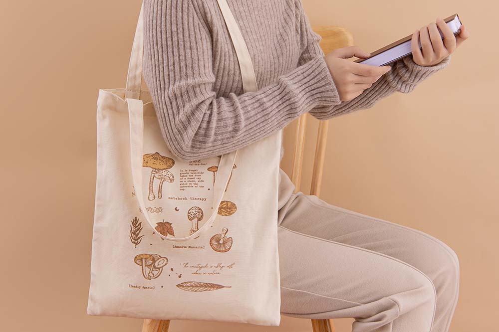 Tsuki ‘Vintage Kinoko’ Tote Bag on model’s arm with Tsuki ‘Nara’ Limited Edition Bullet Journal held in hands in beige background