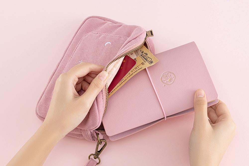 Tsuki ‘Sakura Journey’ Travel Pouch with Tsuki ‘Sakura Journey’ Limited Edition Travel Notebook inside held in hands on pink background