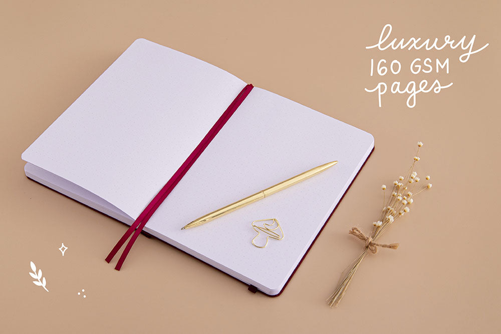Open page spread of Tsuki ‘Kinoko’ Limited Edition Bullet Journal with luxury 160GSM pages and free paperclip gift with gold pen and dried flowers on beige background