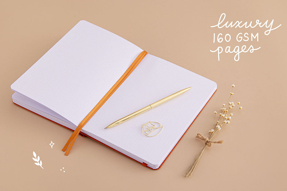 Open page spread of Tsuki ‘Kitsune’ Limited Edition Fox Bullet Journal with luxury 160GSM pages and free paperclip gift with gold pen and dried flowers on beige background
