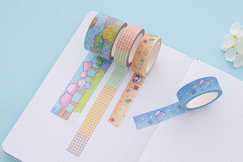 Tsuki ‘Four Seasons’ Washi Tapes by Notebook Therapy x Milkkoyo rolled out on open bullet journal page with white flower on light blue background