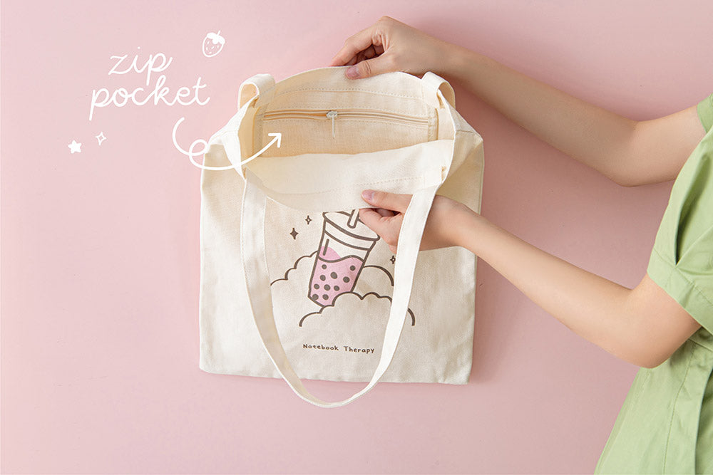 Tsuki ‘Ichigo’ Boba Tote Bag held in hands with inside zippable pocket in light pink background