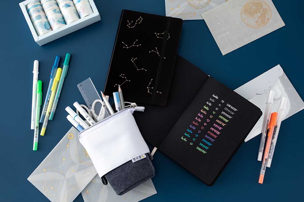 Open Tsuki Black Paper Limited Edition Hardcover Bullet Journal with black page Constellations notebook with washi set and sticker sheets with Gelly Roll Pens on dark blue background