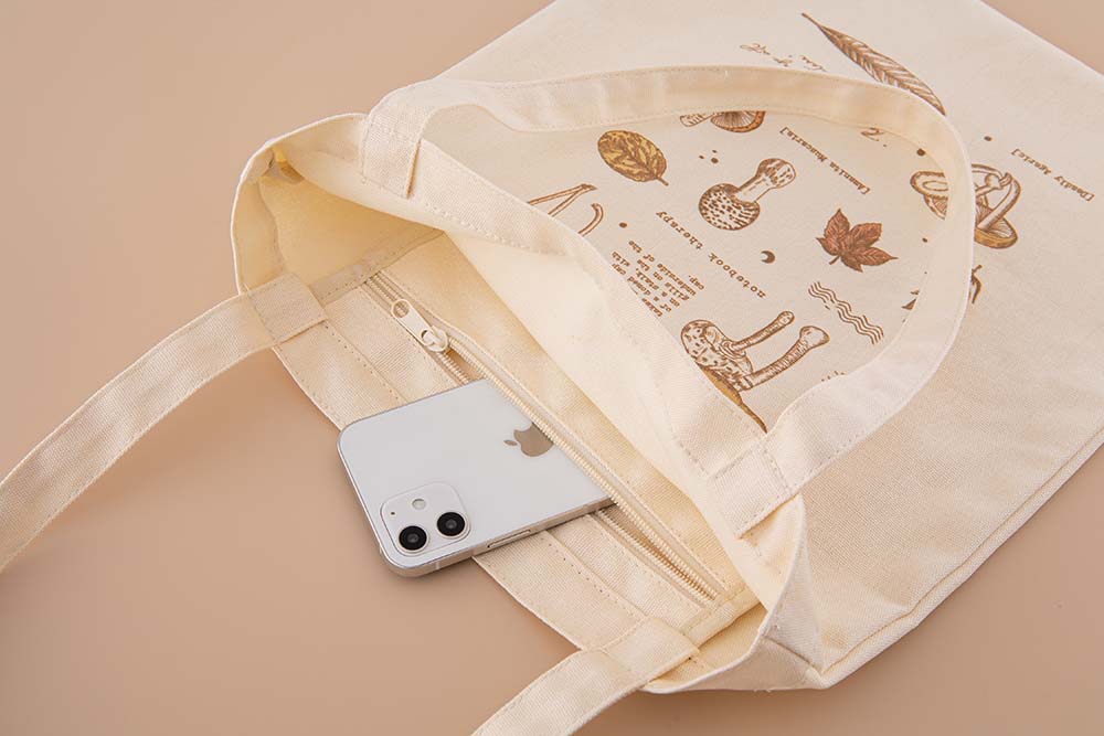 Tsuki ‘Vintage Kinoko’ Tote Bag with zippable pocket with mobile phone on beige background