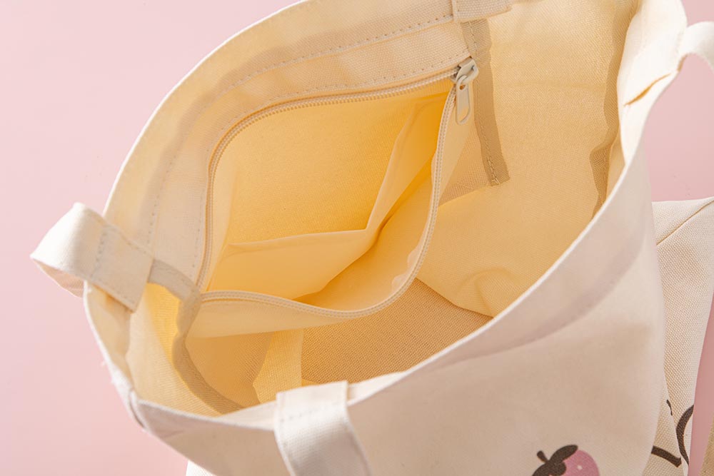 Close up of the inside of Tsuki ‘Ichigo Boba’ Tote Bag with inside zippable pocket in light pink background