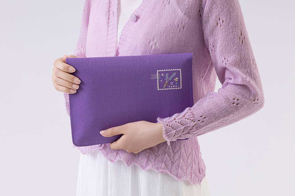 Person wearing lilac knitted jumper carrying the purple notebook pouch showing the design at the back