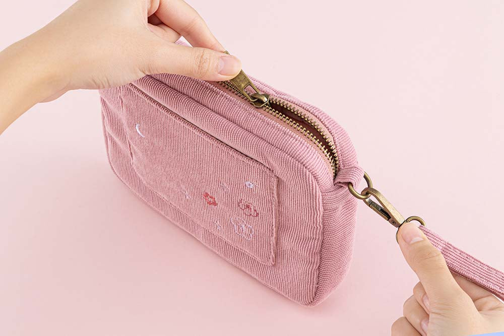 Tsuki ‘Sakura Journey’ Travel Pouch held in hands in pink background