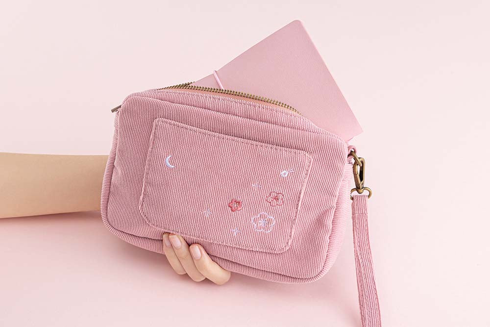 Tsuki ‘Sakura Journey’ Travel Pouch with Tsuki ‘Sakura Journey’ Limited Edition Travel Notebook held in hands in pink background