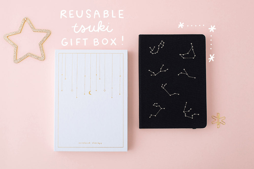 Reusable gift box and constellation themed black notebook on a pink background