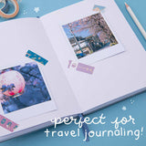Polaroid photo on a notebook with washi tapes and “perfect for travel journaling” written in white