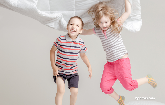 Young girl and boy jumping on the bed 