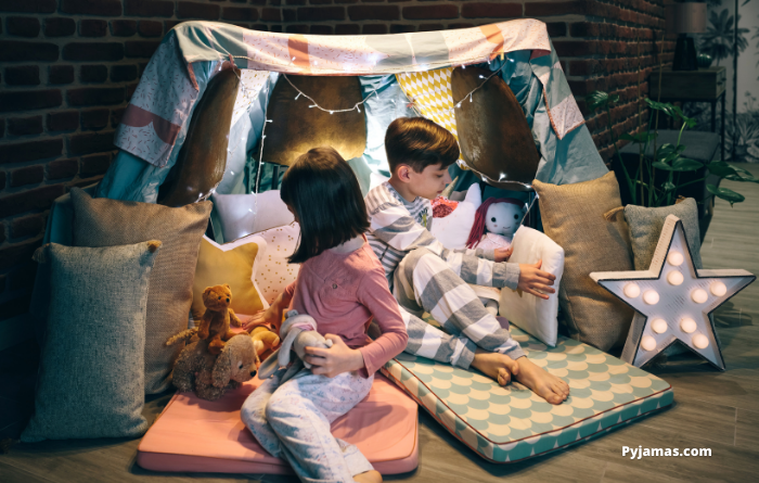 Young girl and boy in fort tent with pillows and mattress 