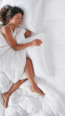 woman laying in bed with pillows and duvet