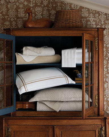 bed linens stacked in an open hall cabinet