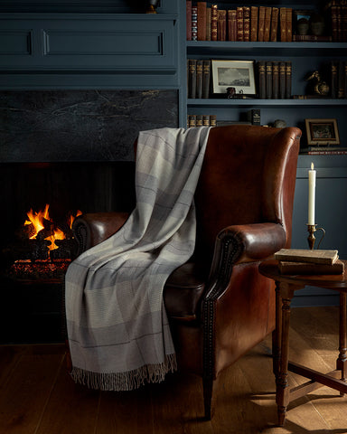 wool blanket on leather chair in study by fireplace