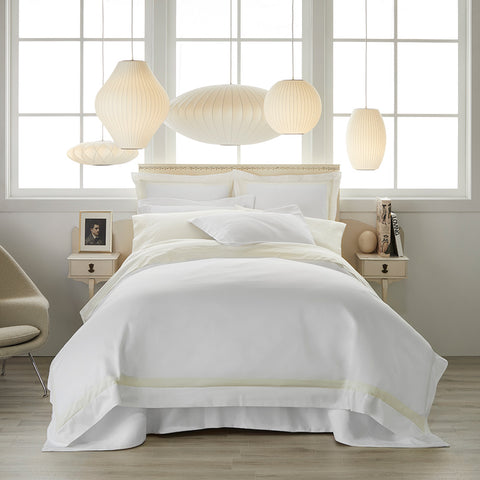 all white bed with several sculptural lanterns hanging over
