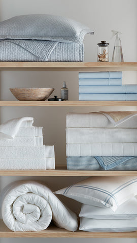 blue and white bedding and bath linens on shelves