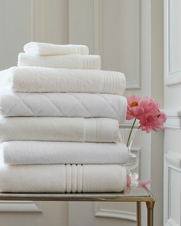stack of different white towels on bathroom side table