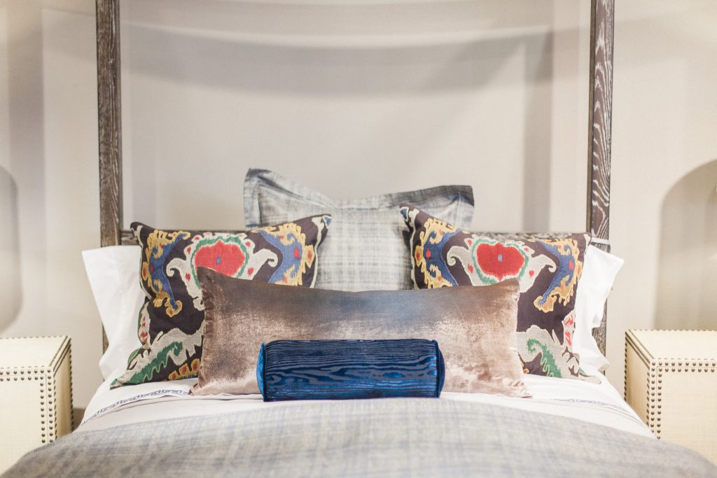 Bedding design by Margaret Chambers with brightly colored accent pillows atop a softly neutral bed