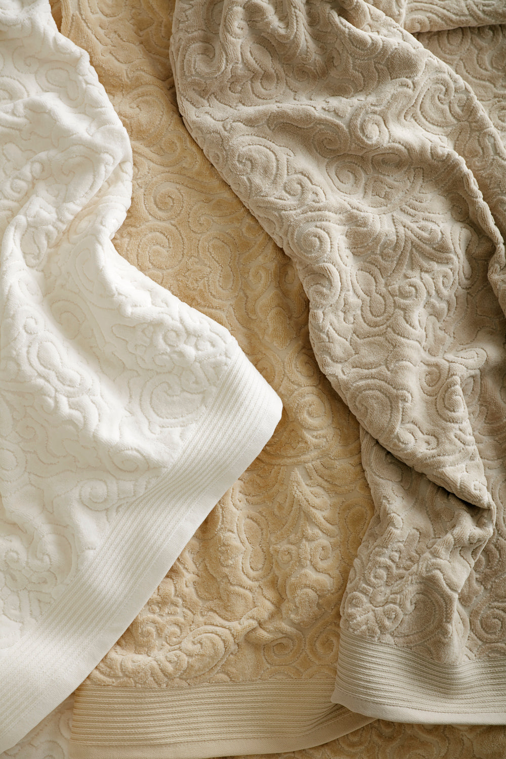 Towels in various neutral colors featuring a retro damask pattern in a sculpted velour