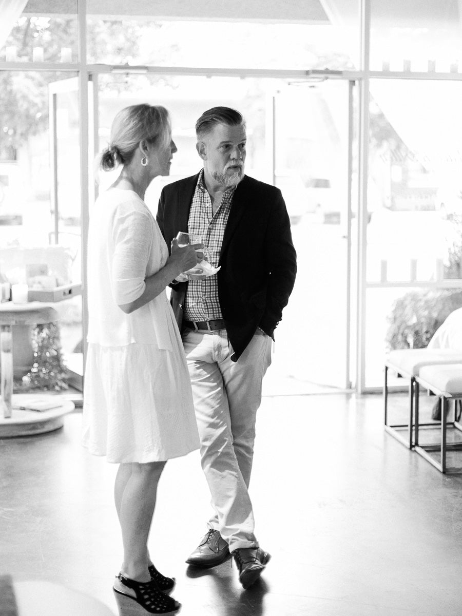 Black and white candid portrait of a man and woman talking in front of open shop doors