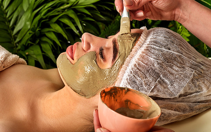 Mud facial mask of woman in spa salon