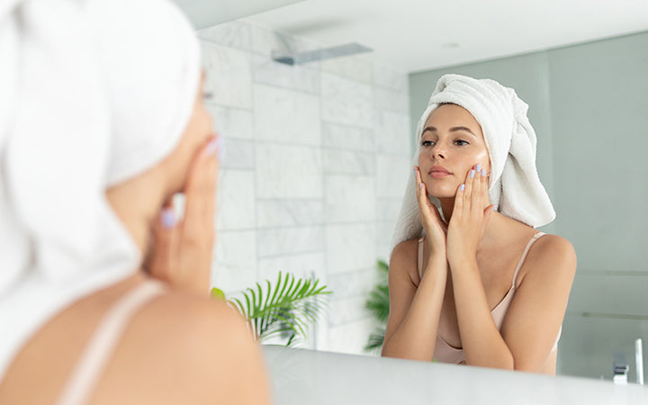 Woman using skin face cream moisturizing lotion after taking bath
